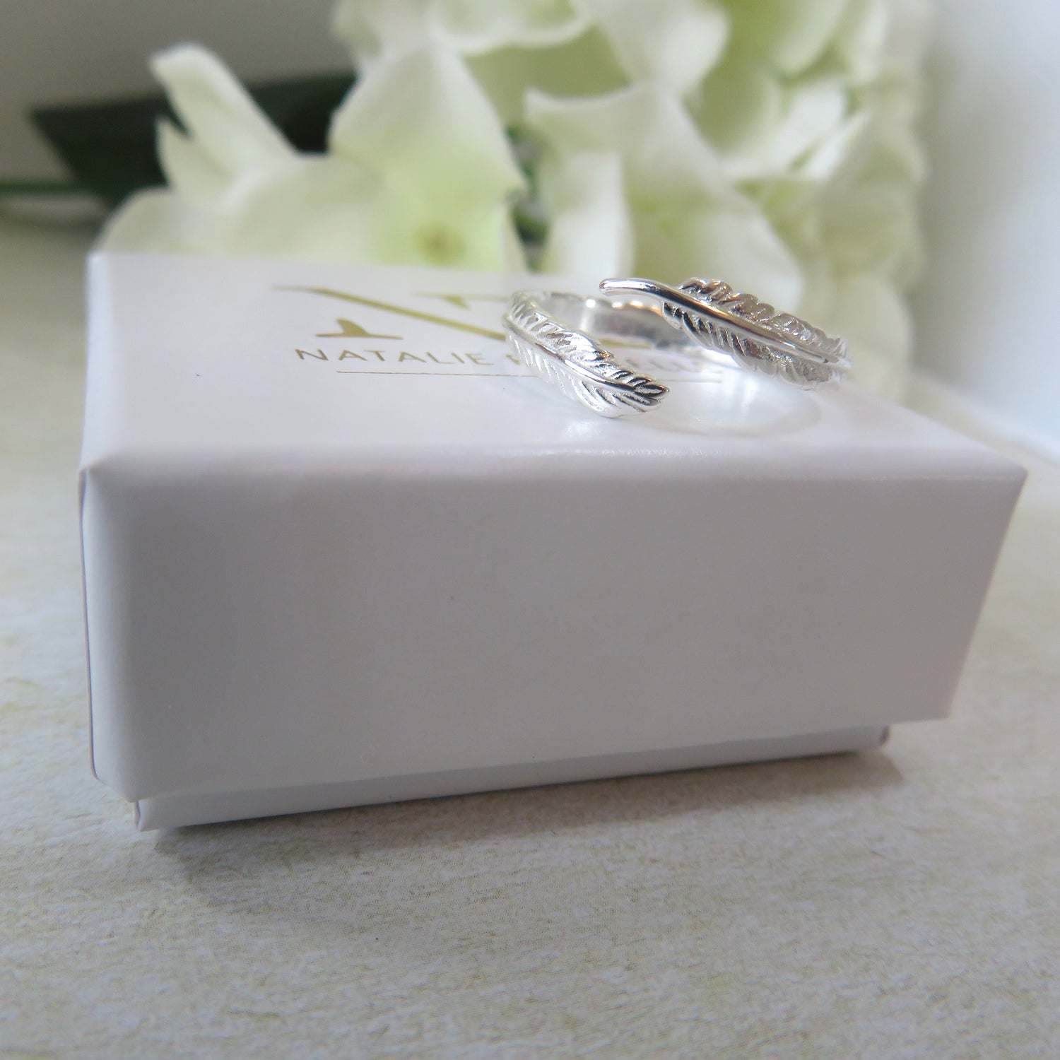Silver ring on a white box with 'Natalie' branding, against a light background.
